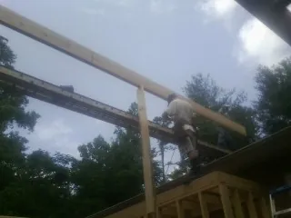 Carpenter setting a ridge beam over a new addition frame — Ice Dam Removal by Roofing Brothers in Koppel