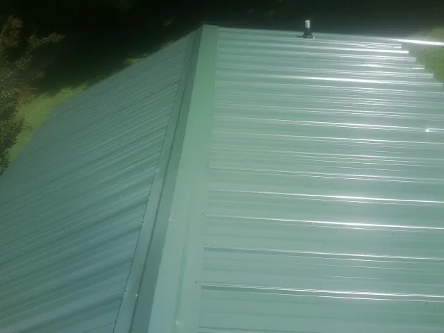 New green metal panels meeting at the ridge of a roof — Flat Roof Repair work by our crew in Koppel