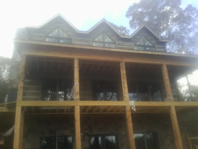 Dormers and porch framing on a large log home under construction — Roof Coating work by our crew in Koppel