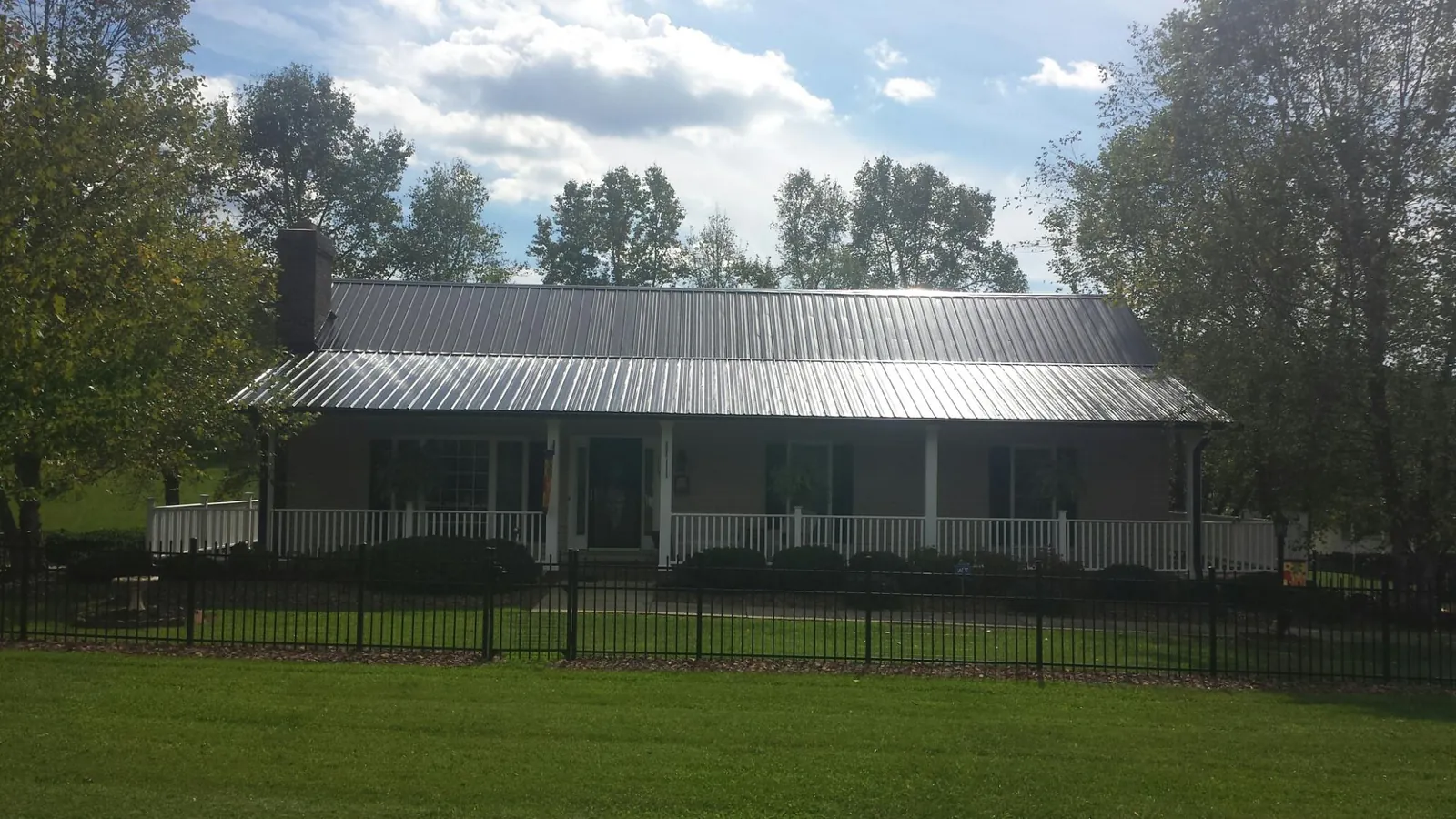 Gray metal roof on a brick ranch with a full width front porch — Gutter Guard Installation work by our crew in Koppel